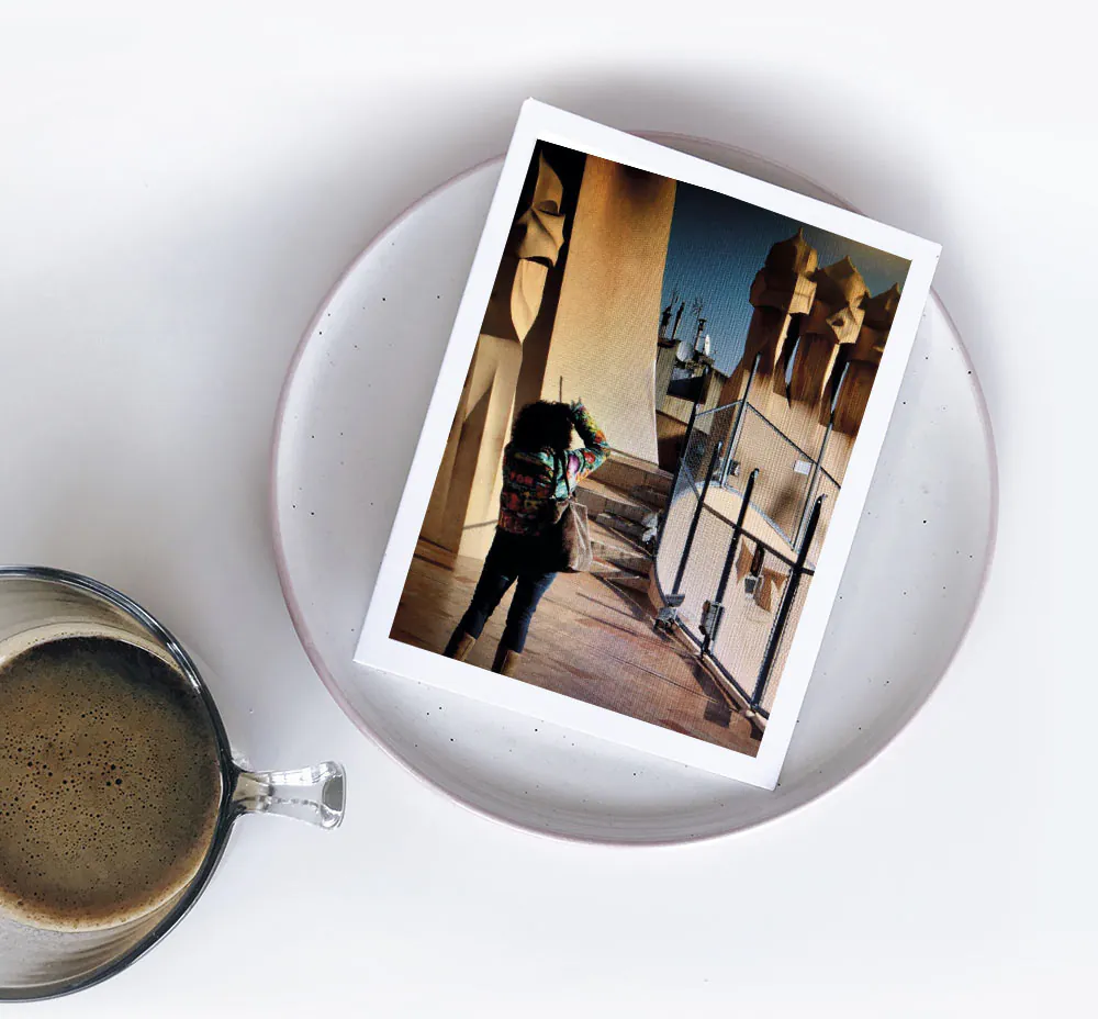 Foto de alguien fotografiando las chimeneas de La Pedrera, sobre un plato junto a un café