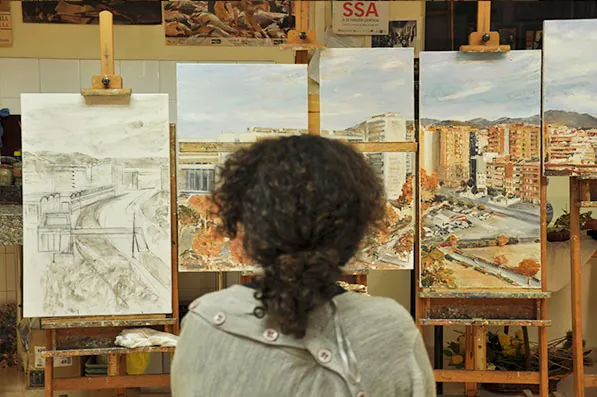 Laura, de espaldas, pintando frente a los lienzos de la serie